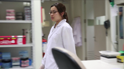 female walking through a science lab wearing a lab coat | Video Production Agency Singapore
