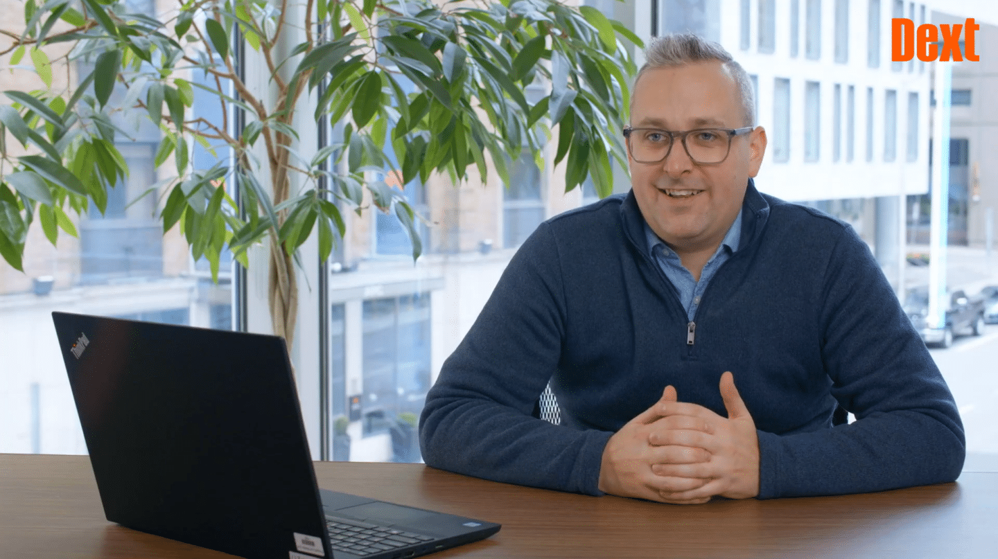 man wearing a blue jacket sat at desk with laptop