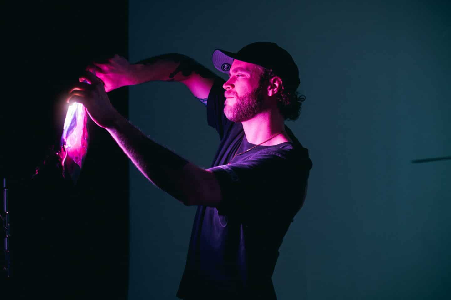 man wearing baseball cap holding up a pink light